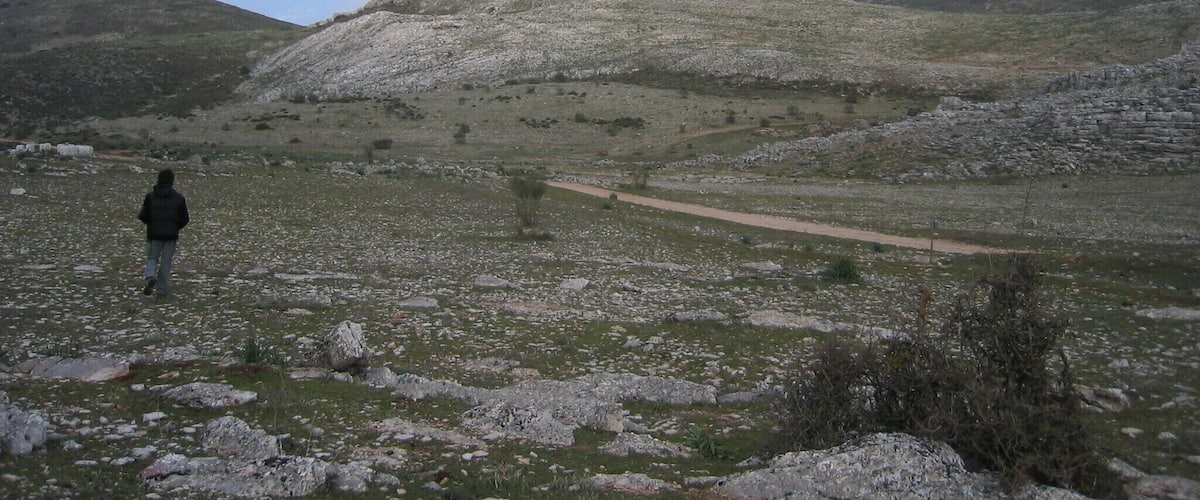 A hilly landscape with a person walking on a dirt path.