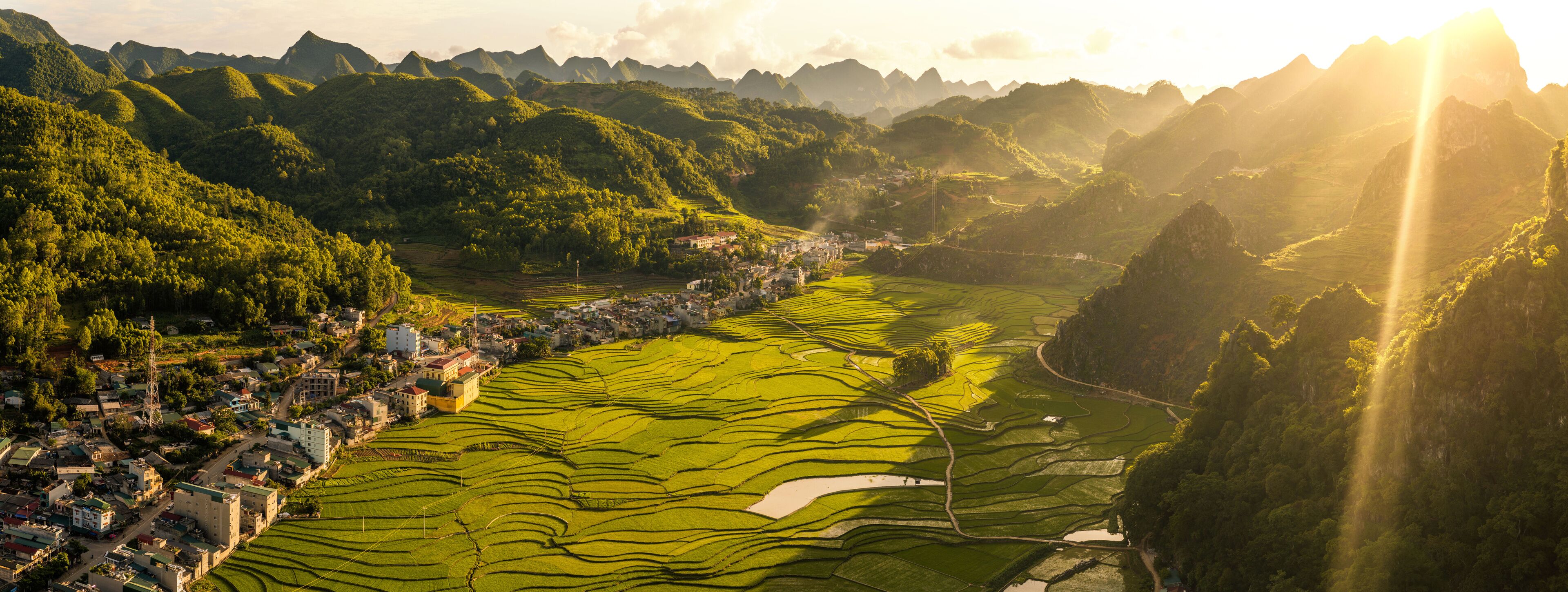 Terraced rice fields, a small town, and surrounding mountains.