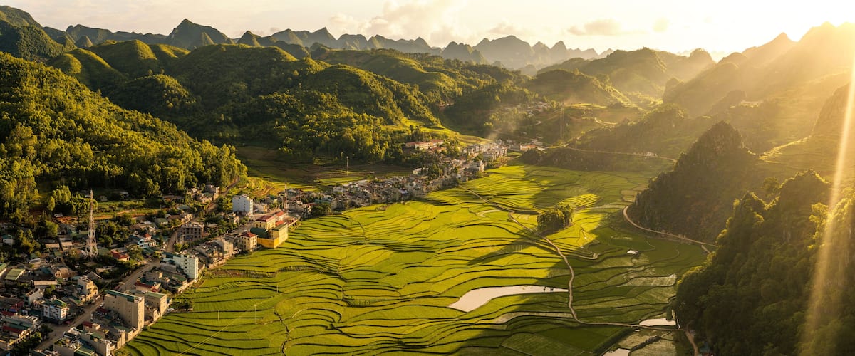 Terraced rice fields, a small town, and surrounding mountains.