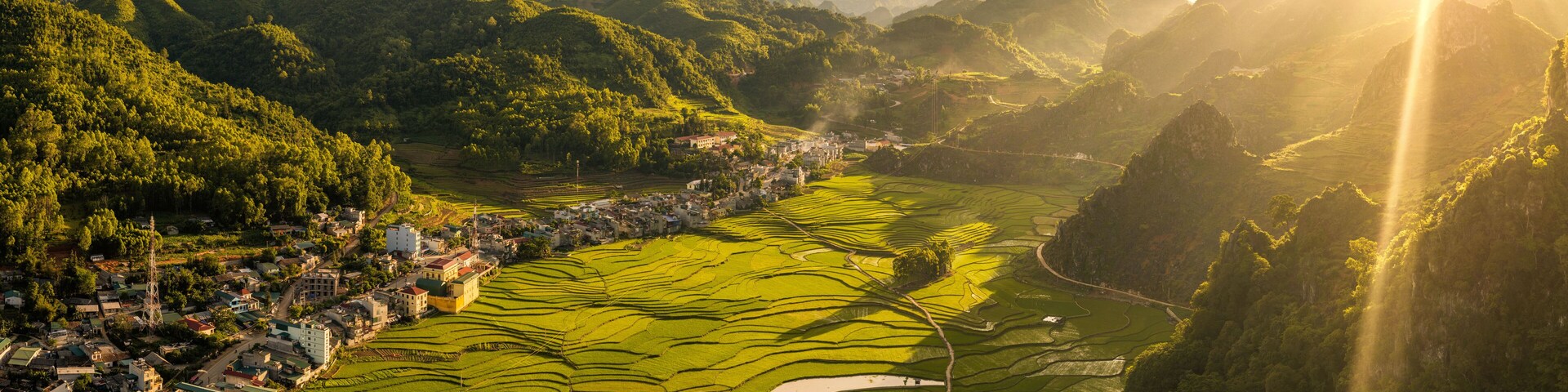 Terraced rice fields, a small town, and surrounding mountains.