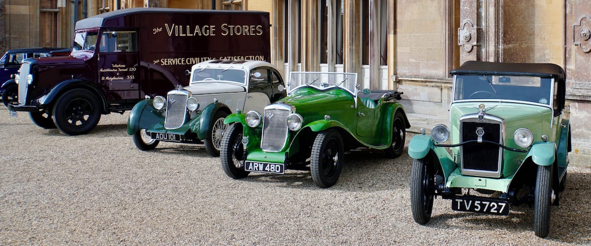 Vintage cars parked in front of a historic building with ornate architecture.