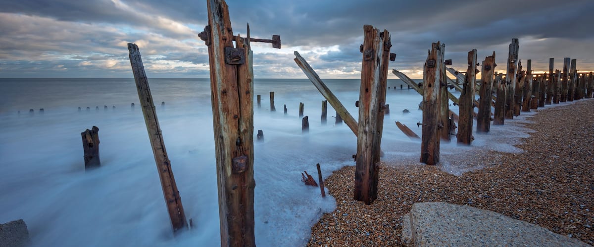 A beach with wooden posts and pebbles.