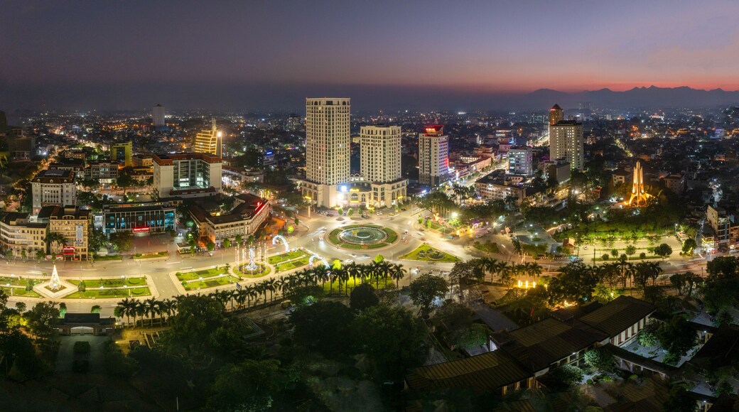Aerial night views of a brightly illuminated central roundabout and surrounding cityscape in Thai Nguyen city, with traffic light trails.
