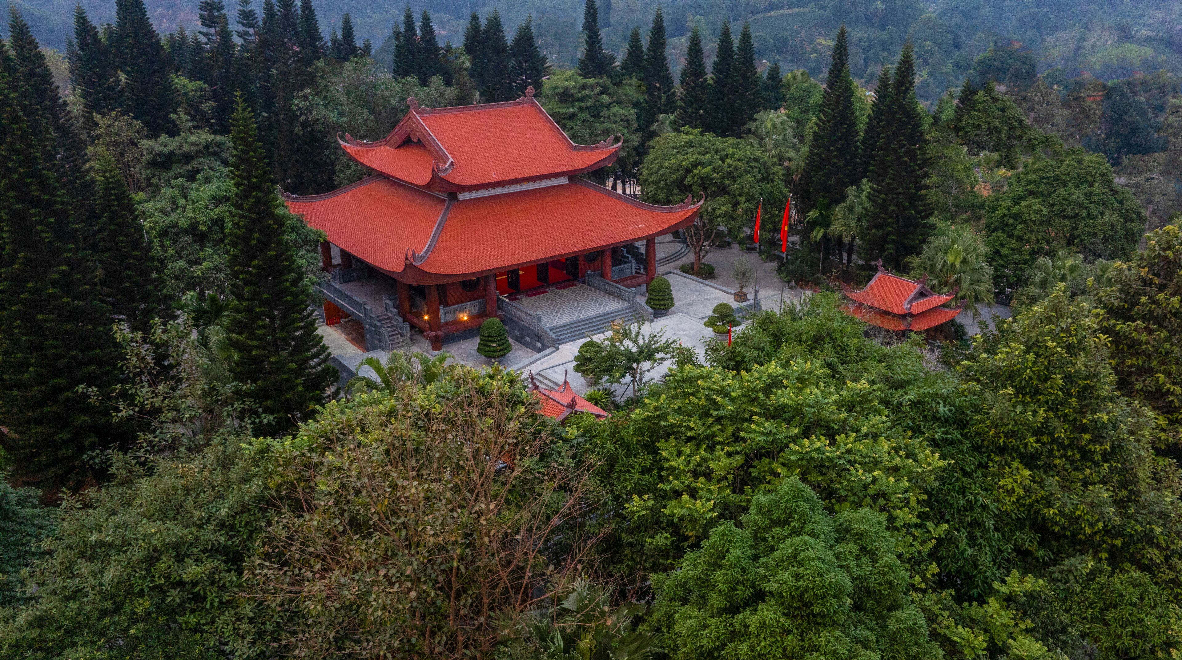 A traditional multi-tiered temple surrounded by dense forest.