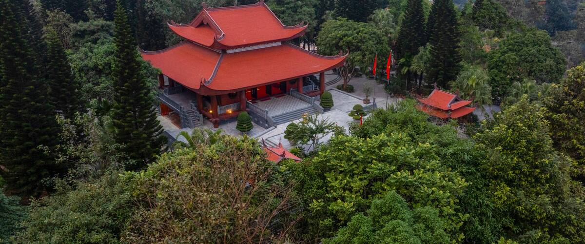 A traditional multi-tiered temple surrounded by dense forest.