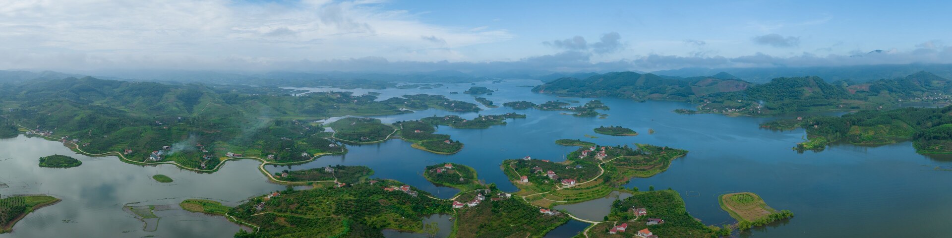 Vista aérea de um lago cercado por inúmeras pequenas ilhas e casas dispersas.