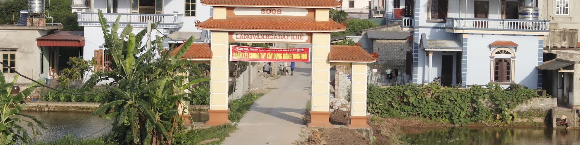 A pathway leading to a building with a sign reading "LANG VANHOADAP KHE".