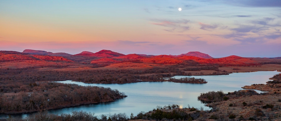 A sunset over a river surrounded by red-hued hills.
