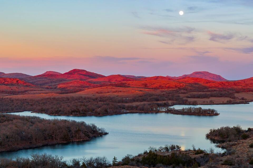 A sunset over a river surrounded by red-hued hills.