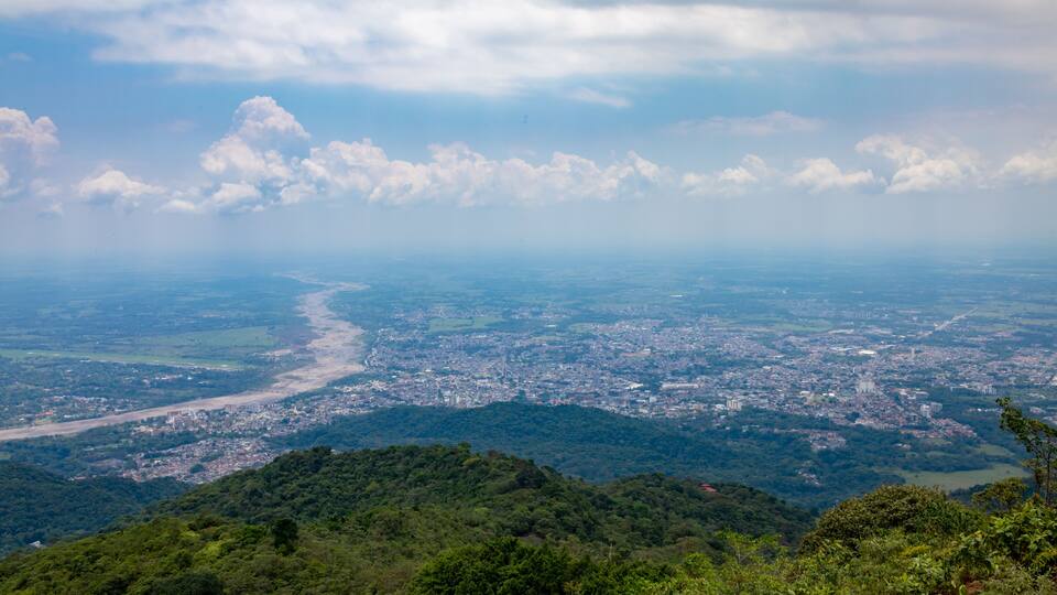 A panoramic view of a city surrounded by lush green hills and a river running through it.