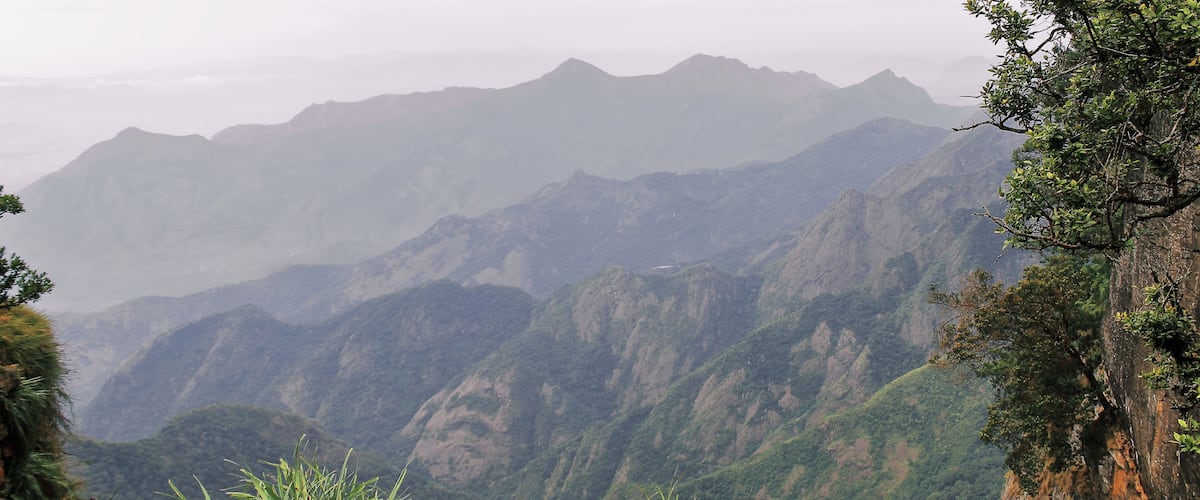 A mountainous landscape with dense vegetation and rocky cliffs.