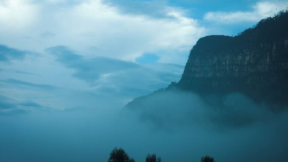 A mountain shrouded in mist with a clear sky above.