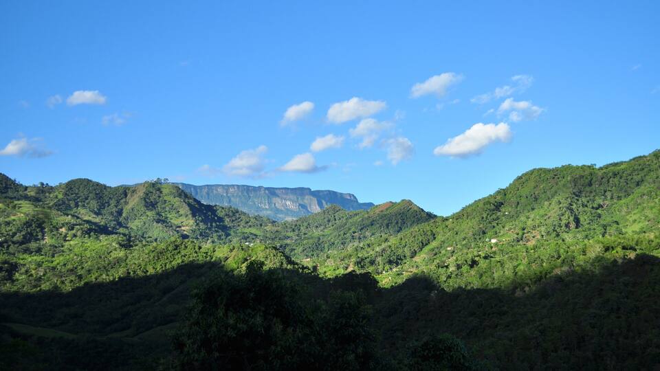 A mountainous landscape with lush greenery and a clear blue sky.