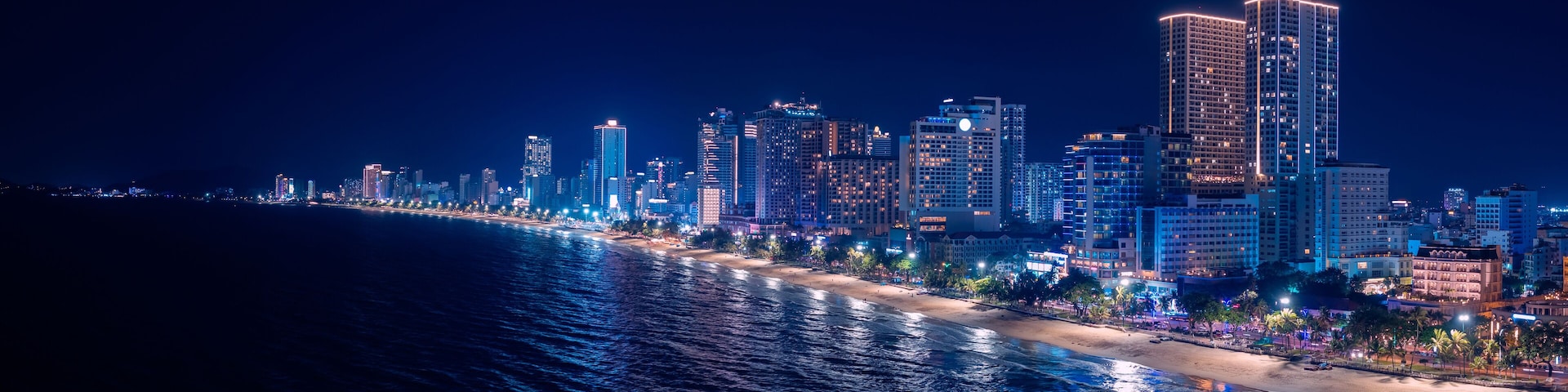 Scenic night aerial view of Nha Trang city with skyscraper neon light and bay of South China Sea in Khanh Hoa province, Vietnam.