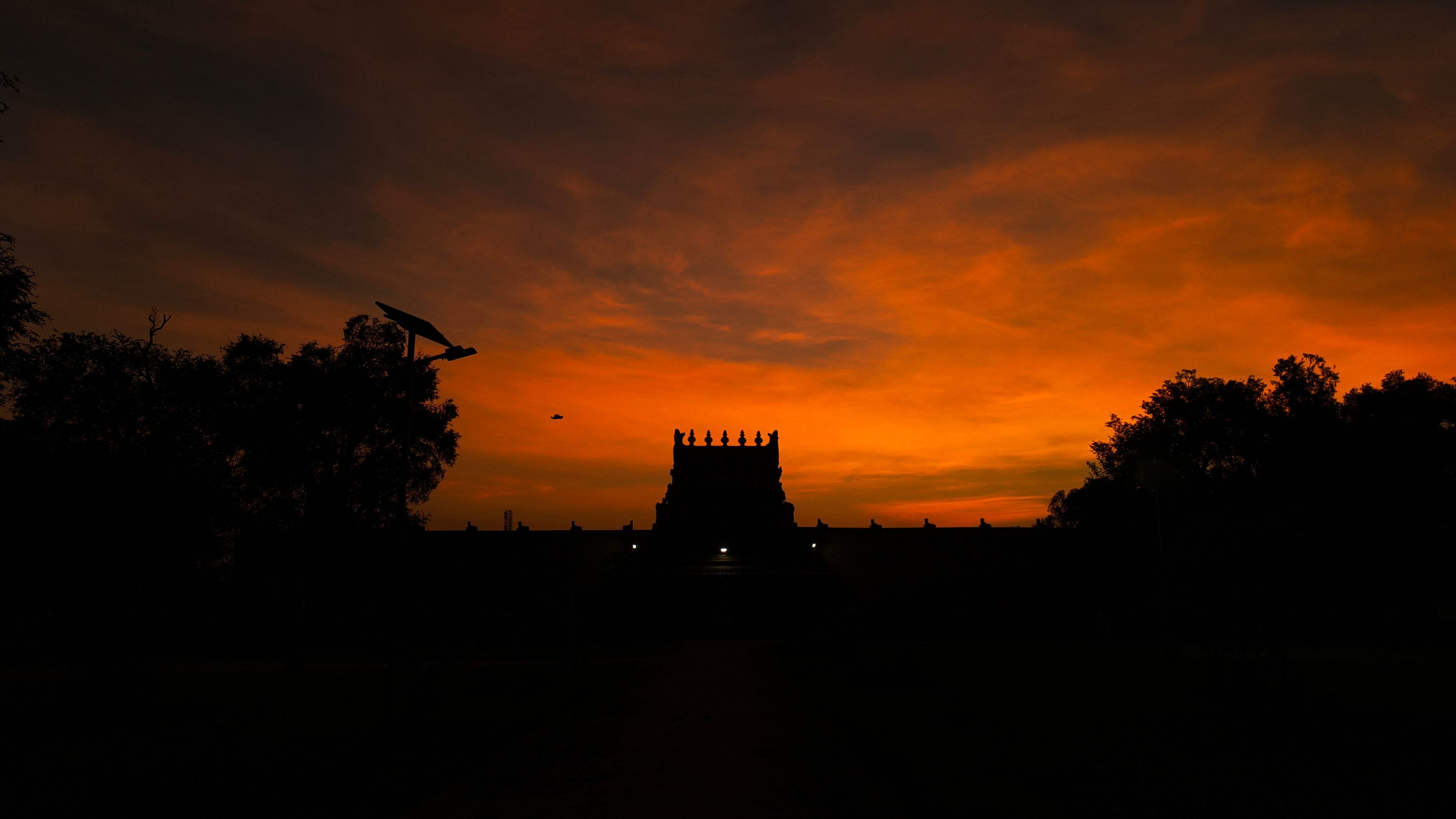 Un coucher de soleil avec la silhouette d’un temple se détachant sur un ciel aux couleurs éclatantes.