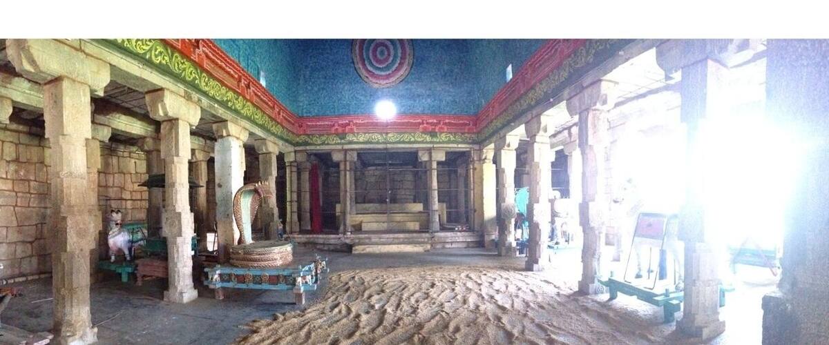 An ancient temple interior with stone pillars, a central altar, and a patterned floor.