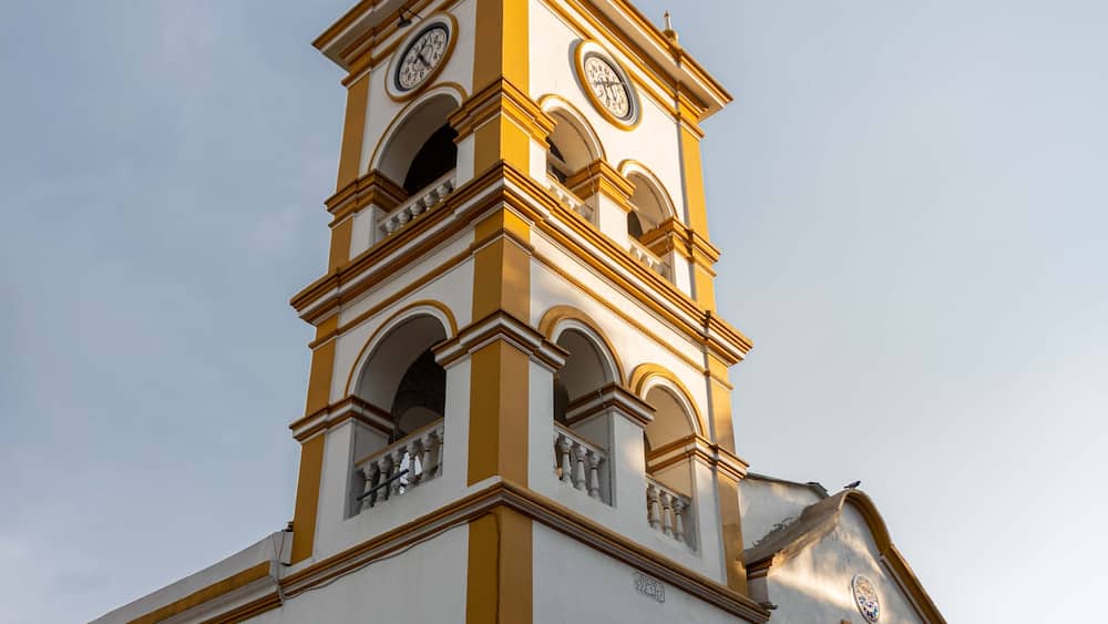A church with a clock tower, arched windows, and a weather vane.