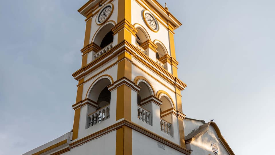 A church with a clock tower, arched windows, and a weather vane.