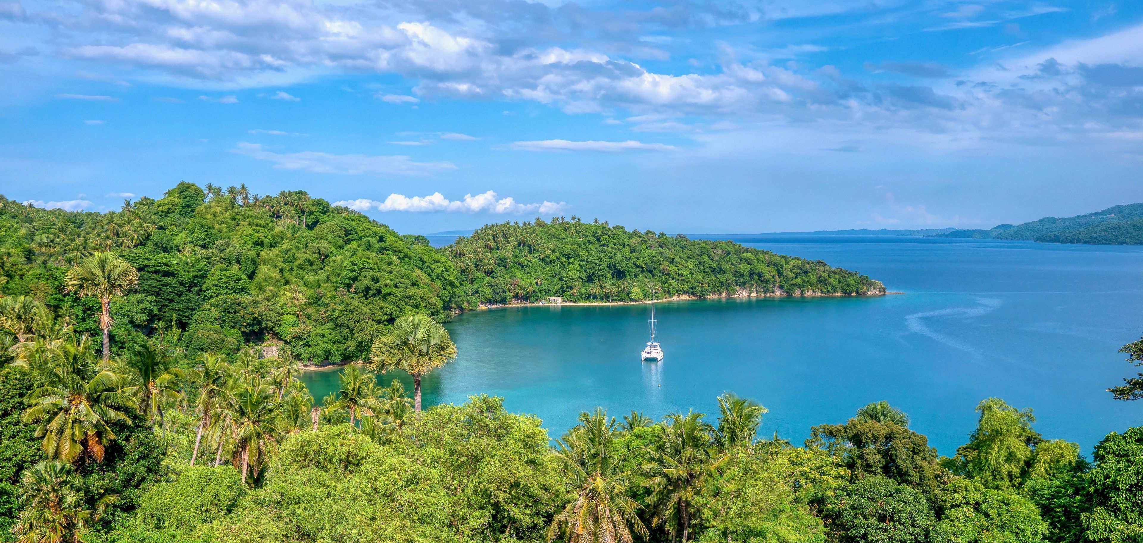 Beautiful tropical landscape scene in Puerto Galera on Mindoro Island, Philippines, showing a yacht anchored in secluded Encenada Bay.