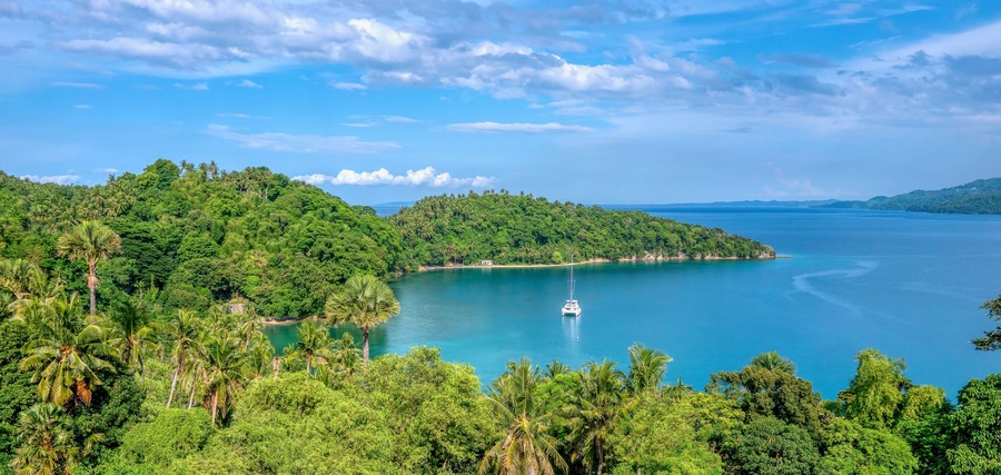 Beautiful tropical landscape scene in Puerto Galera on Mindoro Island, Philippines, showing a yacht anchored in secluded Encenada Bay.