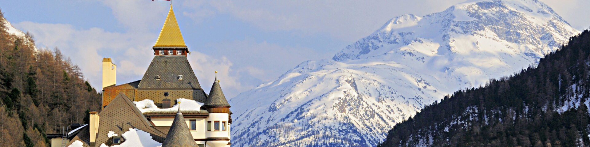 A snow-covered mountain, a castle with a flag, and a town with buildings.