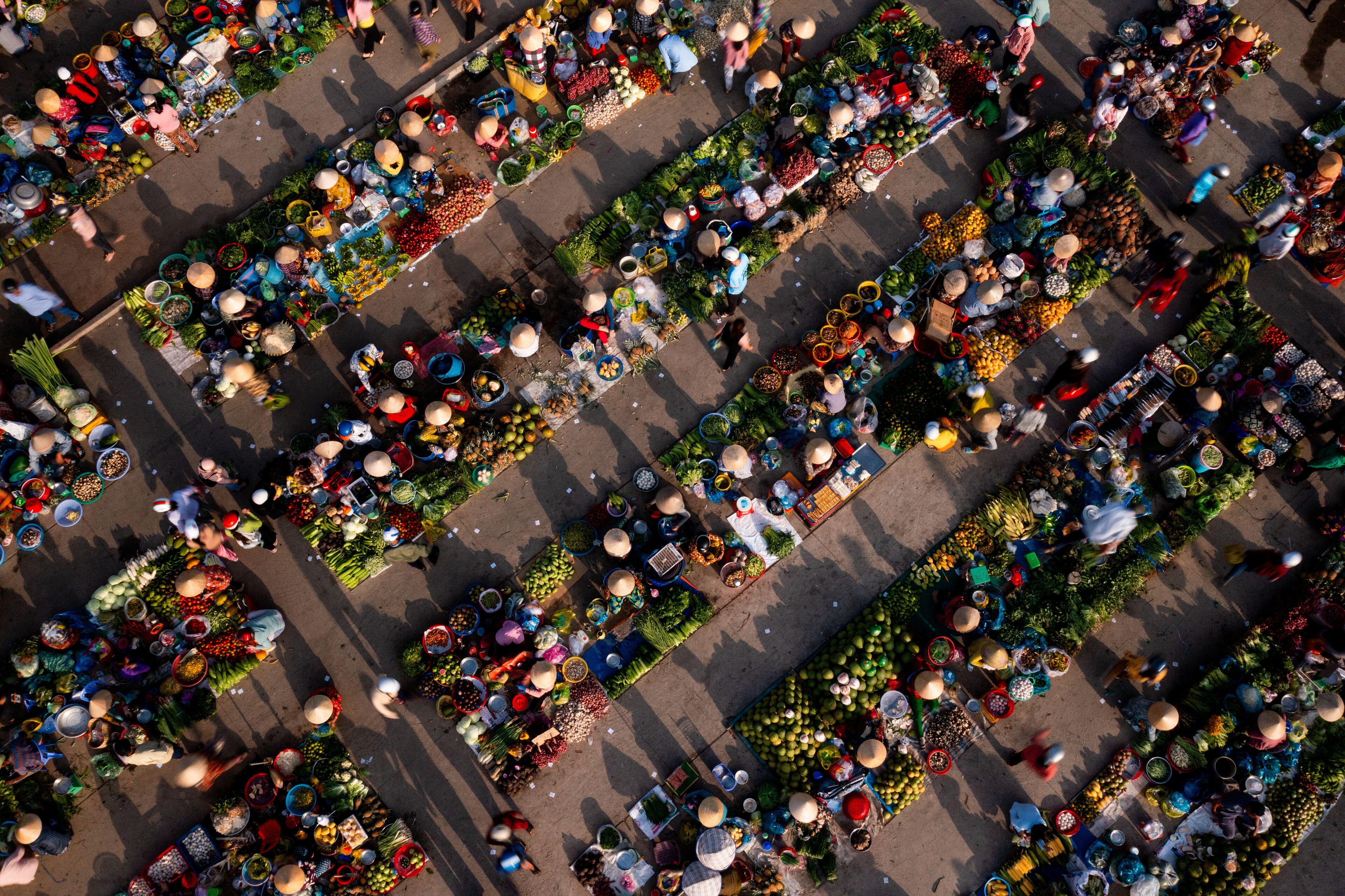 An aerial view of a bustling market with rows of vendors selling fruits, vegetables, and other goods.