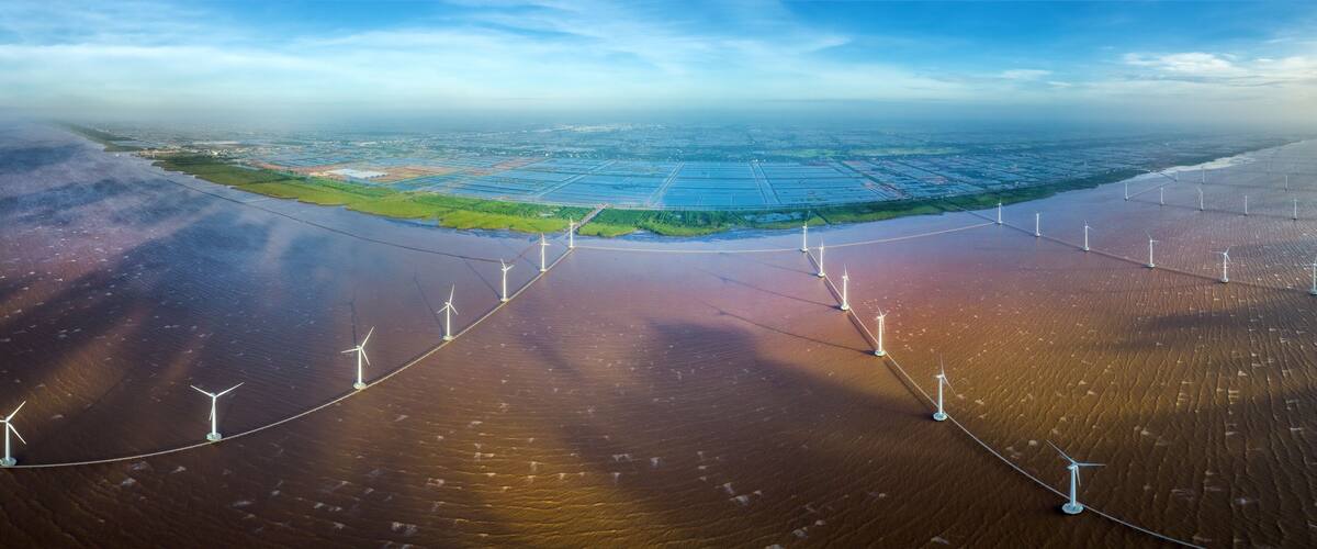 An aerial view of a coastal area with wind turbines and solar panels.