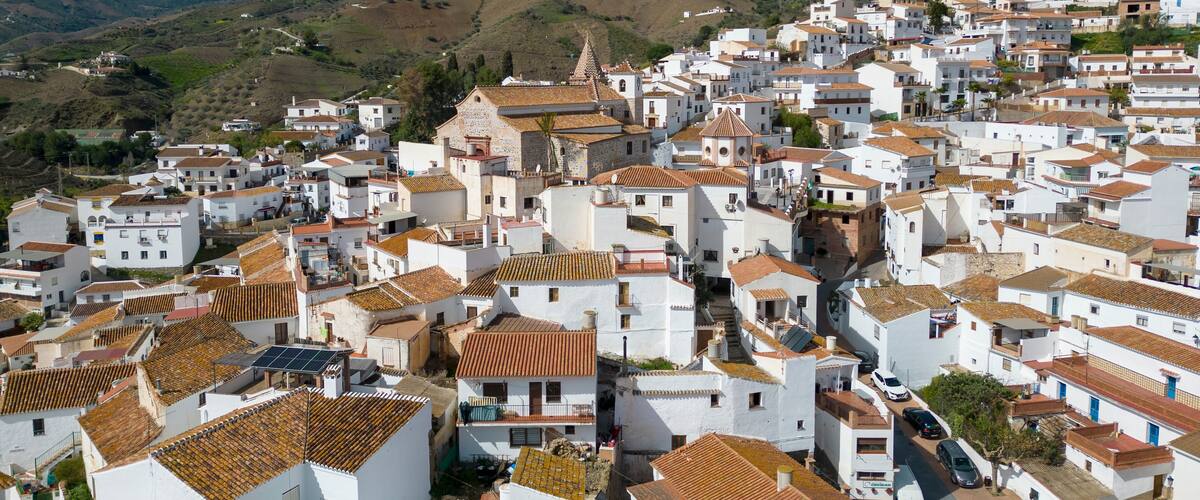 A hillside town with white buildings and terracotta roofs.