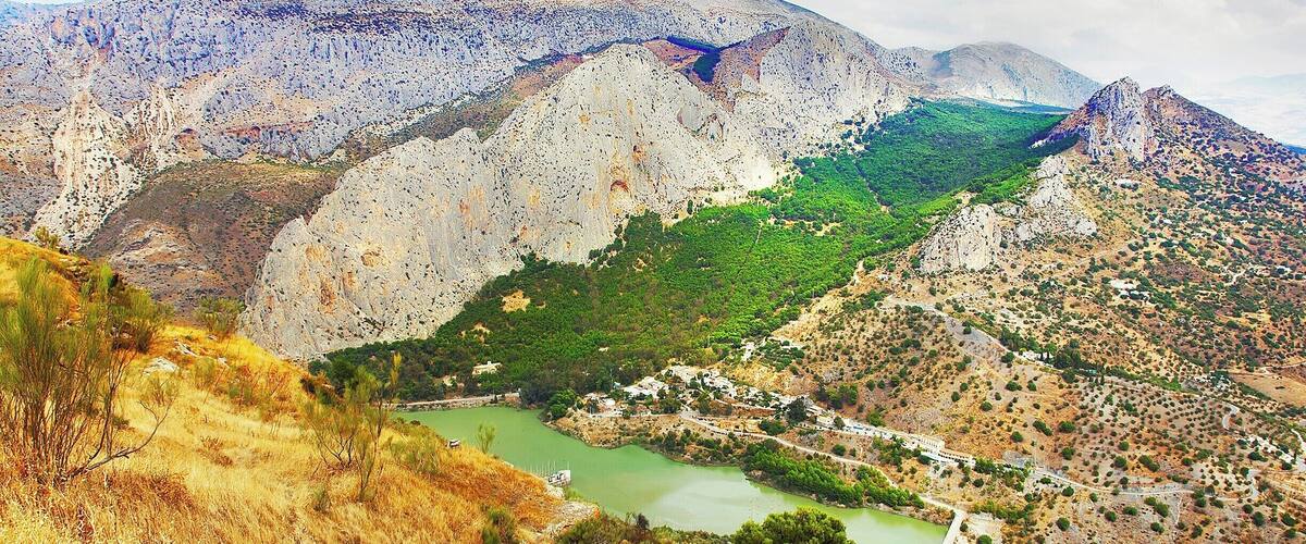 A mountainous landscape with a green valley, a river, and a small settlement.