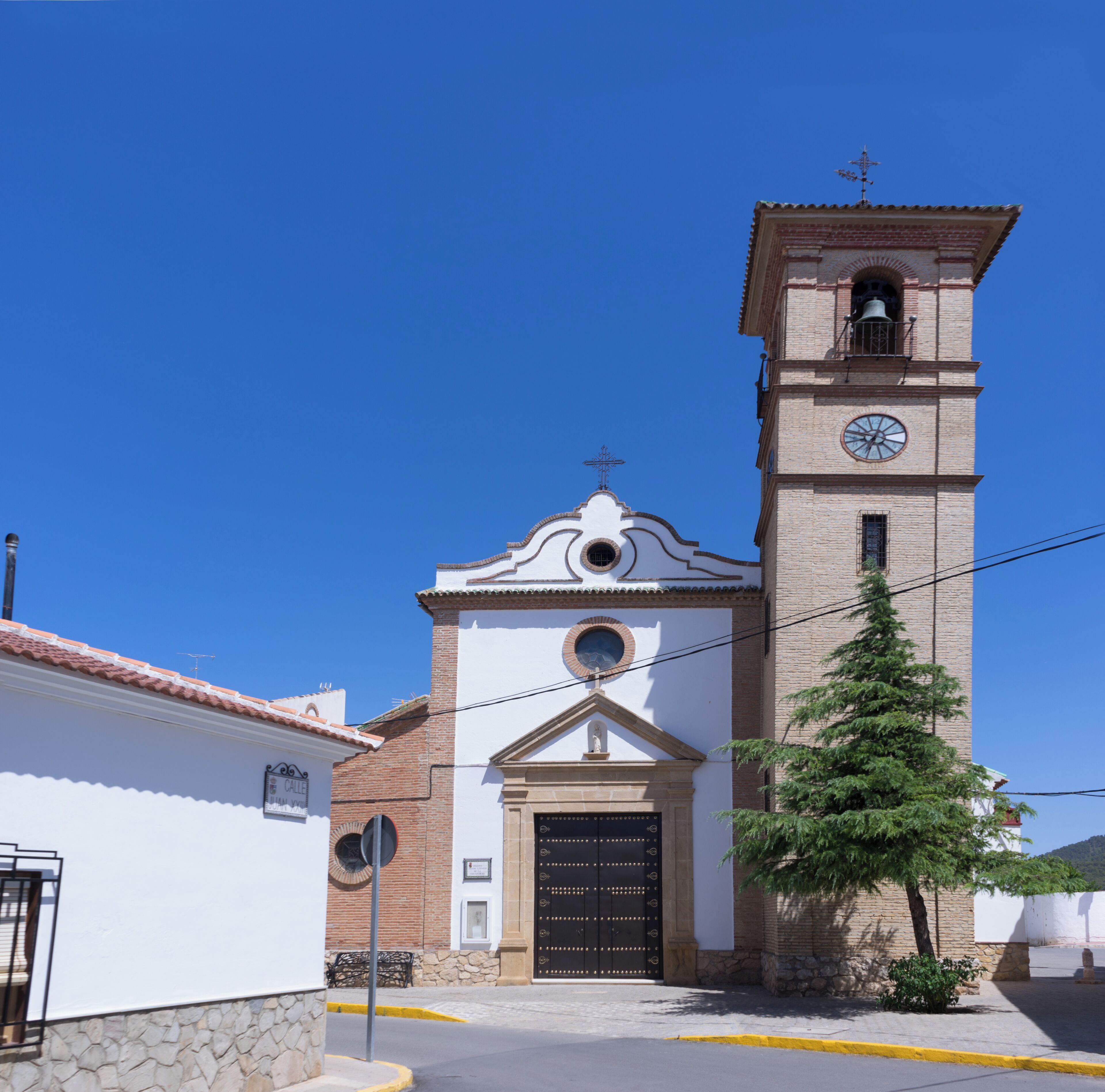 A church with a clock tower, a bell, and a cross on top.