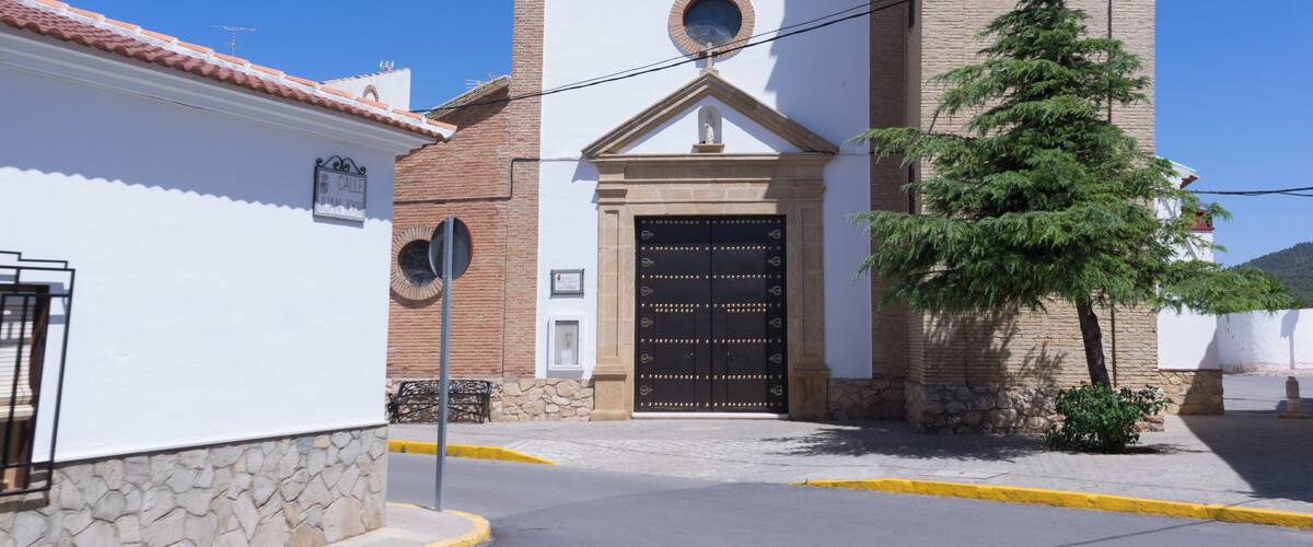 A church with a clock tower, a bell, and a cross on top.