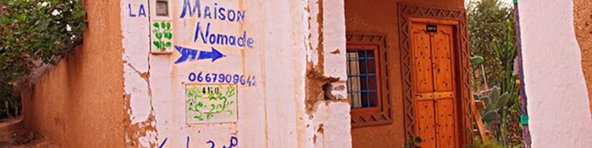Un edificio rústico con puerta de madera y un letrero con texto en varios idiomas.