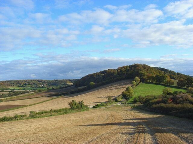 Farmland, Saunderton Looking down over stubble on the southeastern slope of Slough Hill. Allnutt's Wood is on the next hill. The village of Bradenham is visible in the distance to the left.