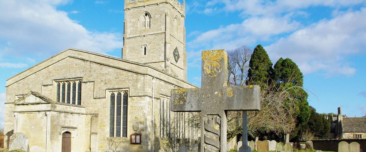 A church with a tall tower and a large cross in the foreground.