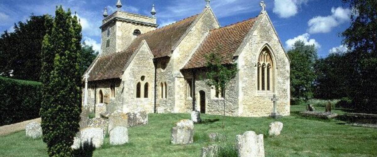 A stone church with a bell tower and a graveyard.