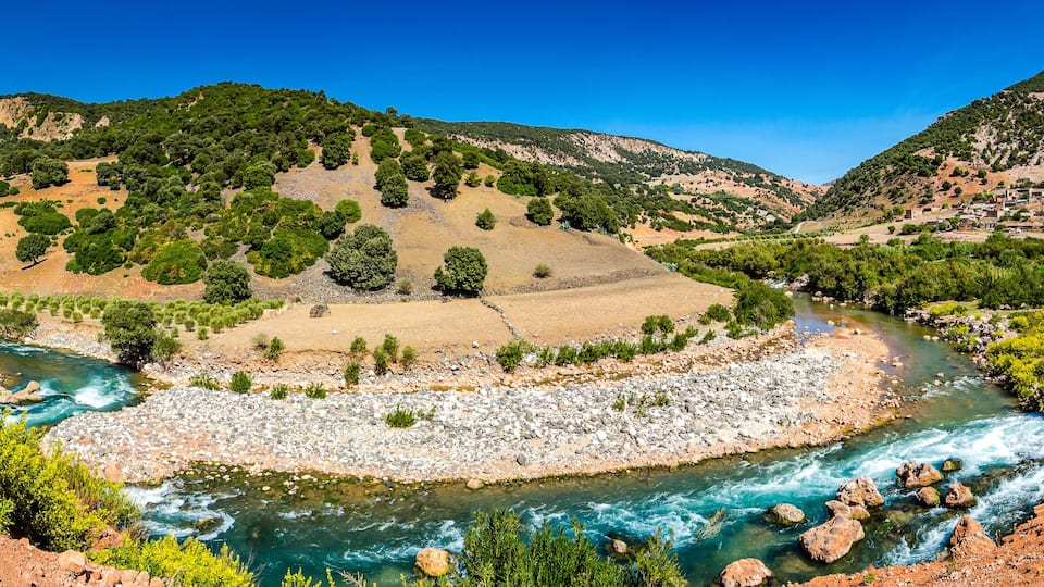 A river winding through a valley with rocky banks and green vegetation.