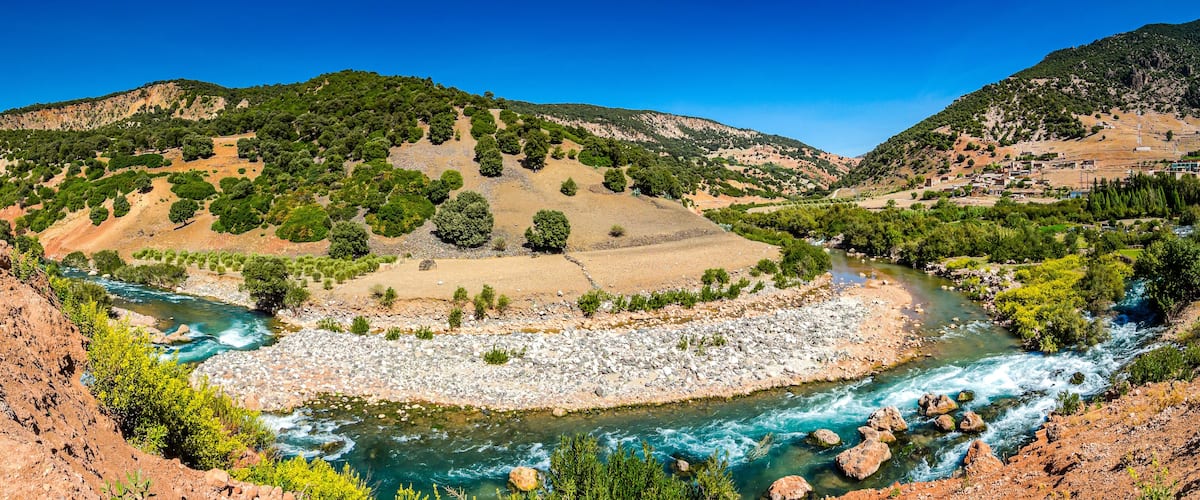 A river winding through a valley with rocky banks and green vegetation.