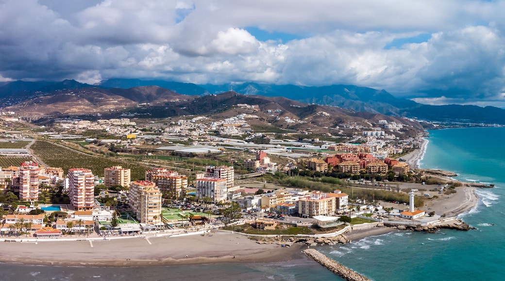 Drone perspective of costal city of Torrox situated in Malaga, Costa del Sol, Spain. Touristic travel destination. View of the promenade and beach area. The lighthouse of Torrox and the river.