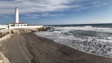 A lighthouse, rocky shoreline, and ocean waves.
