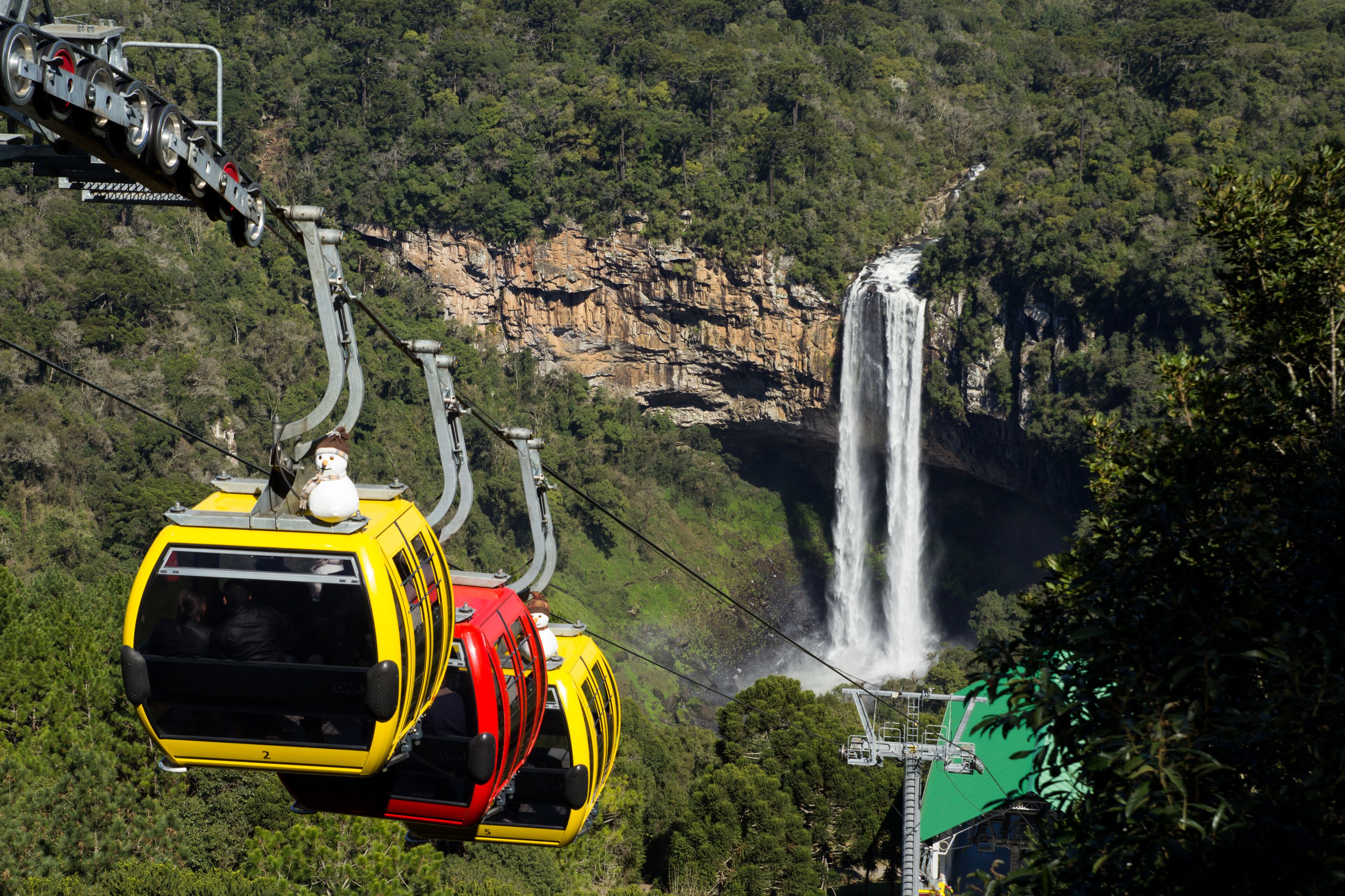 A cable car system with a waterfall in the background.