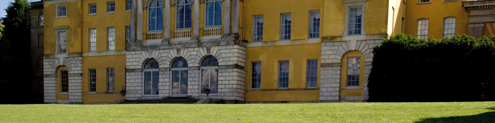 Un edificio grande, amarillo, con ventanas arqueadas y una entrada central.