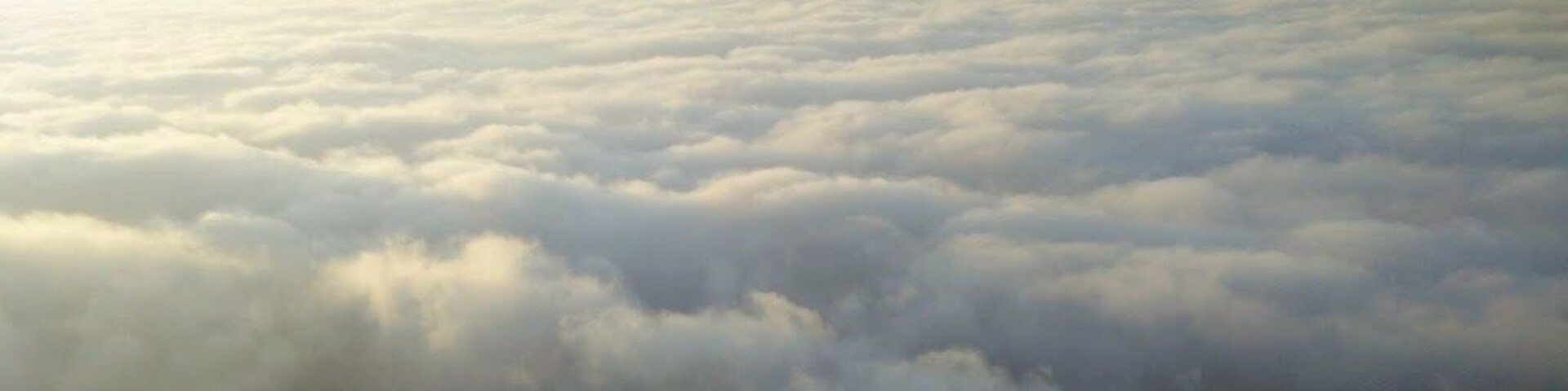 Un extenso mar de nubes bajo una colina cubierta de hierba.