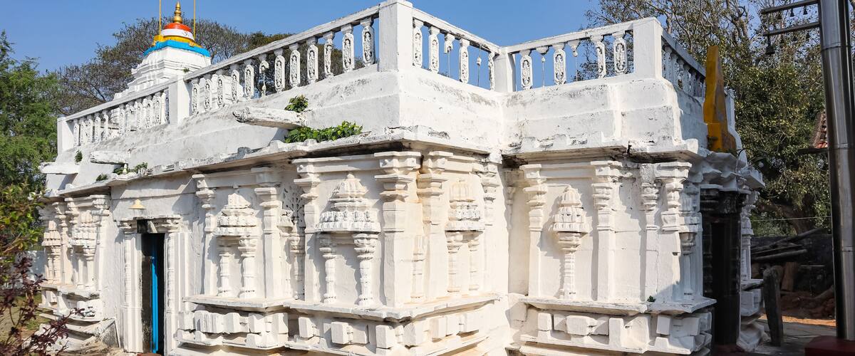 A white temple with intricate carvings and a blue door.