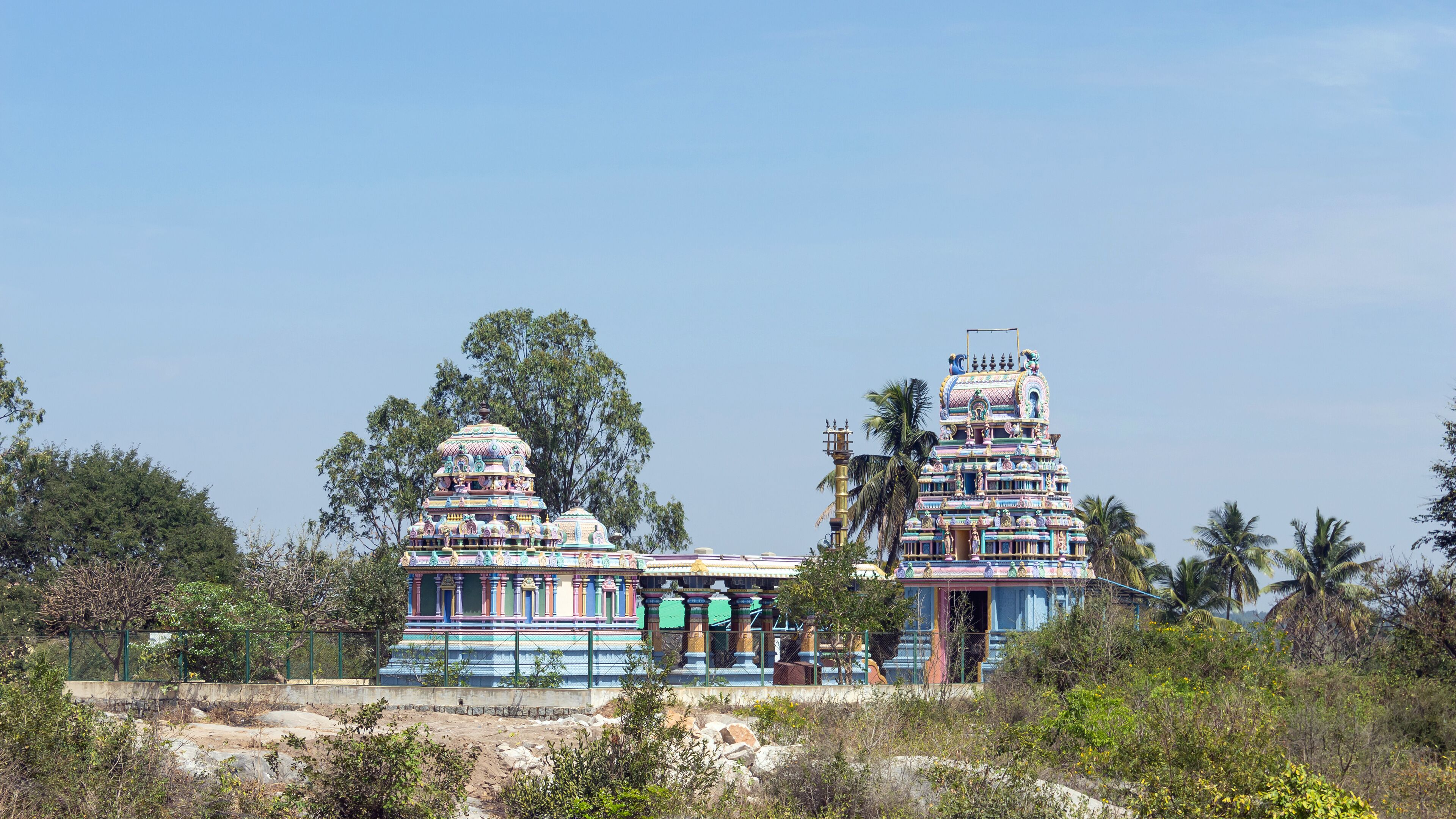 A temple with two towers, surrounded by trees and vegetation.