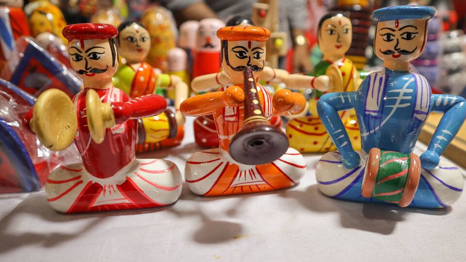 A collection of colorful ceramic figurines with distinct facial features and clothing patterns.