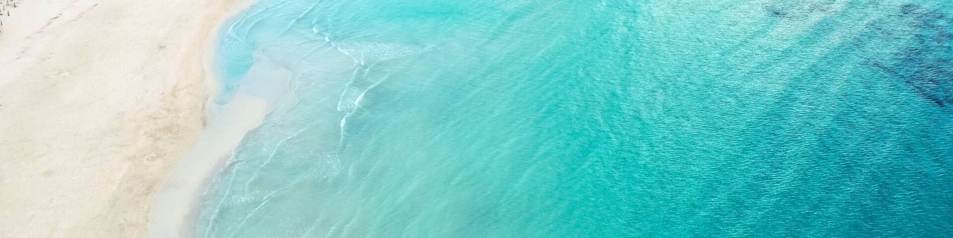 A beach with clear turquoise water and white sand.