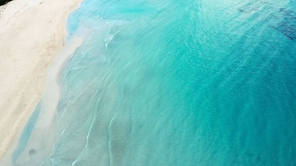 A beach with clear turquoise water and white sand.