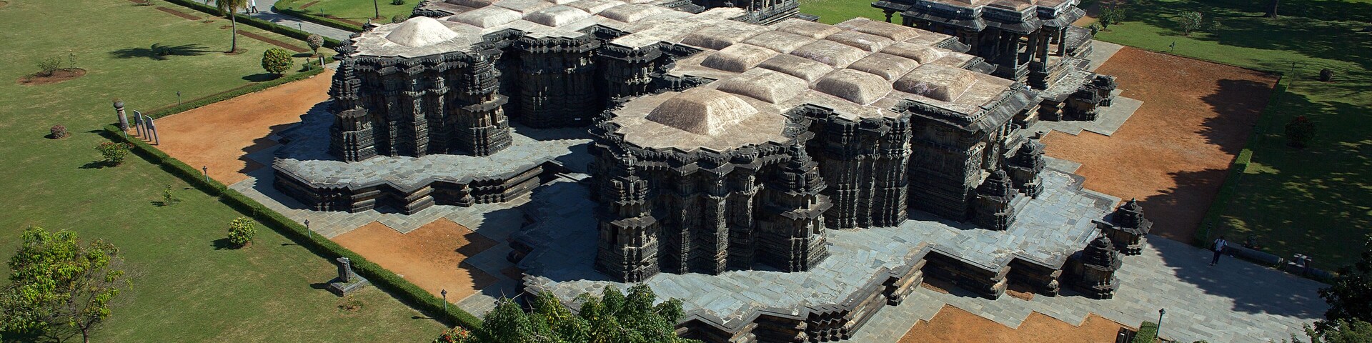 Aerial view of the ancient, elaborately carved Ishvara Temple complex standing majestically amidst lush greenery, Arasikere, Karnataka, India.