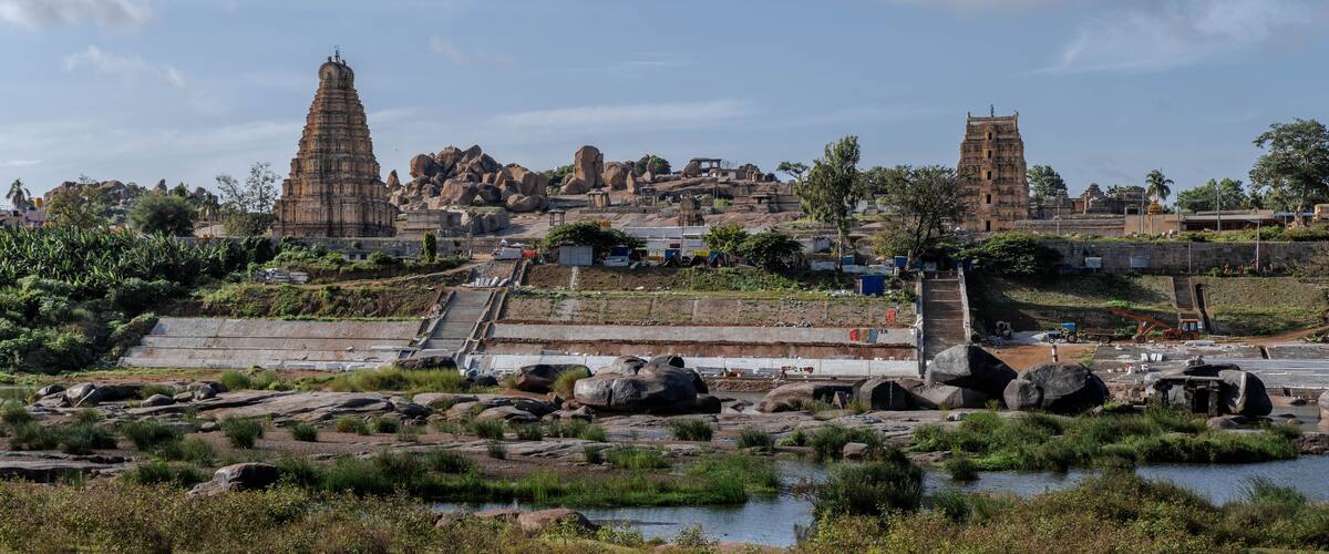 A temple complex with large rock formations and a river in the foreground.