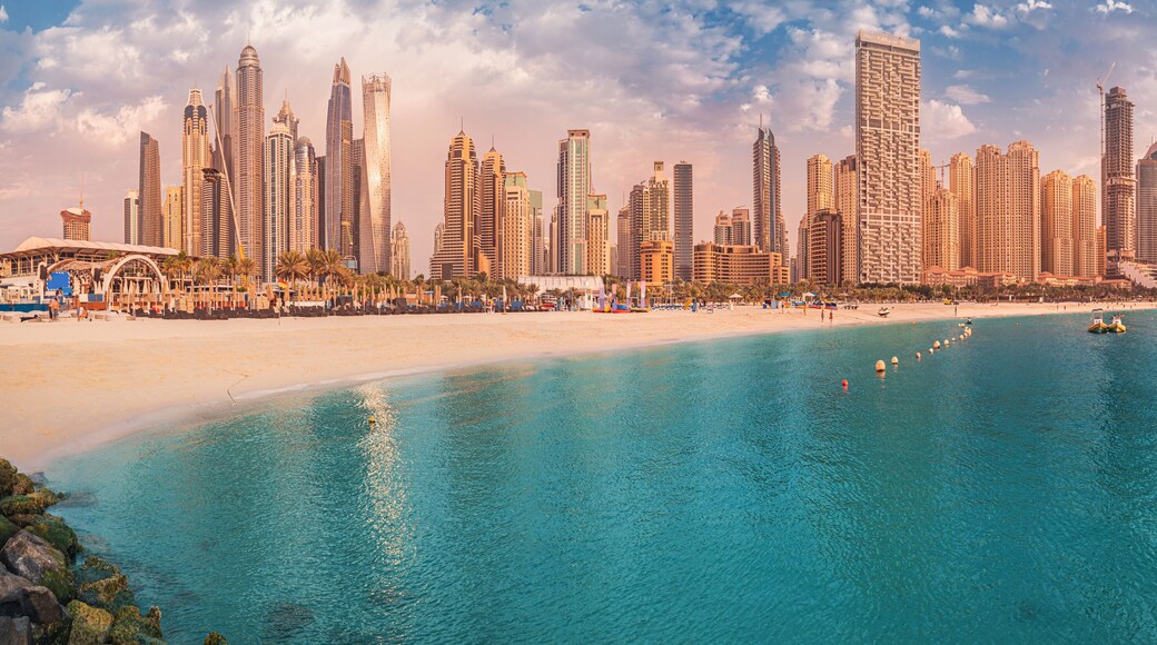 Cityscape panorama of the golden sand illuminated by the setting sun in the JBR beach area. Amazing skyscrapers and azure waters of the Persian Gulf are waiting for visitors